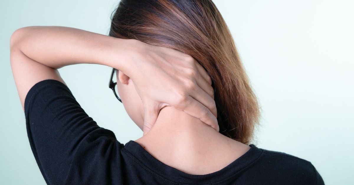 Rear view of a woman massaging her neck, depicting neck pain relief or self-care concepts.