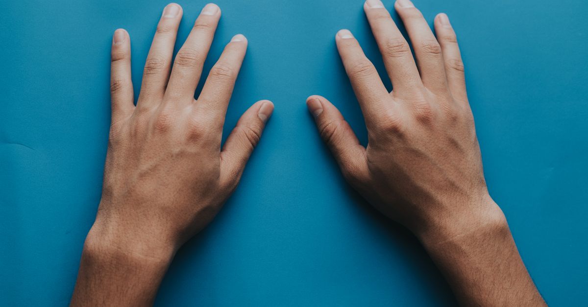 Two adult hands placed on a blue surface, captured in close-up.