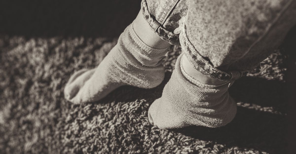 Relaxing feet in socks and jeans on a carpet, enjoying cozy indoor atmosphere.