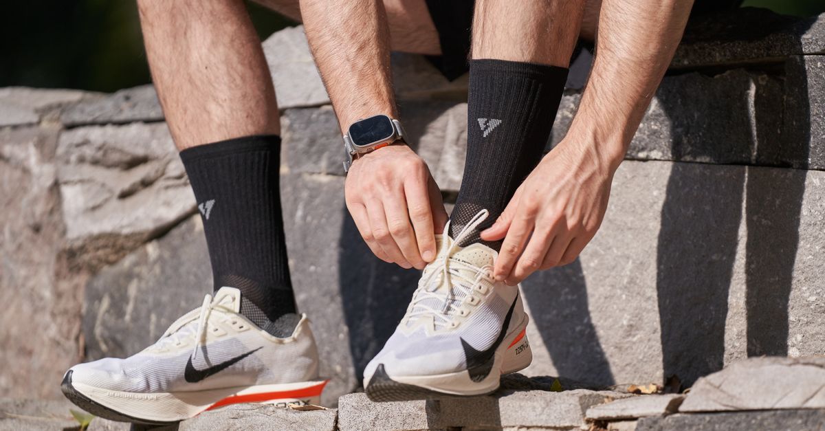 Close-up of a man tying his running shoes on stone steps, preparing for a run outdoors.