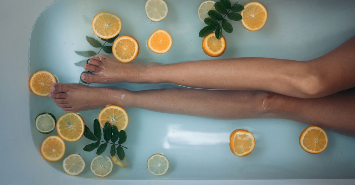 A soothing spa experience with citrus slices and legs submerged in a bathtub, epitomizing relaxation and self-care.