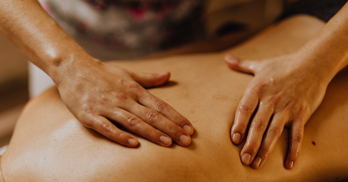 Close-up of hands giving a soothing back massage in a calm setting.