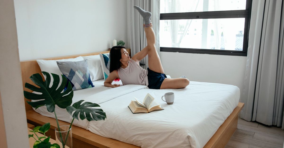 Woman lying on a bed stretching her leg.
