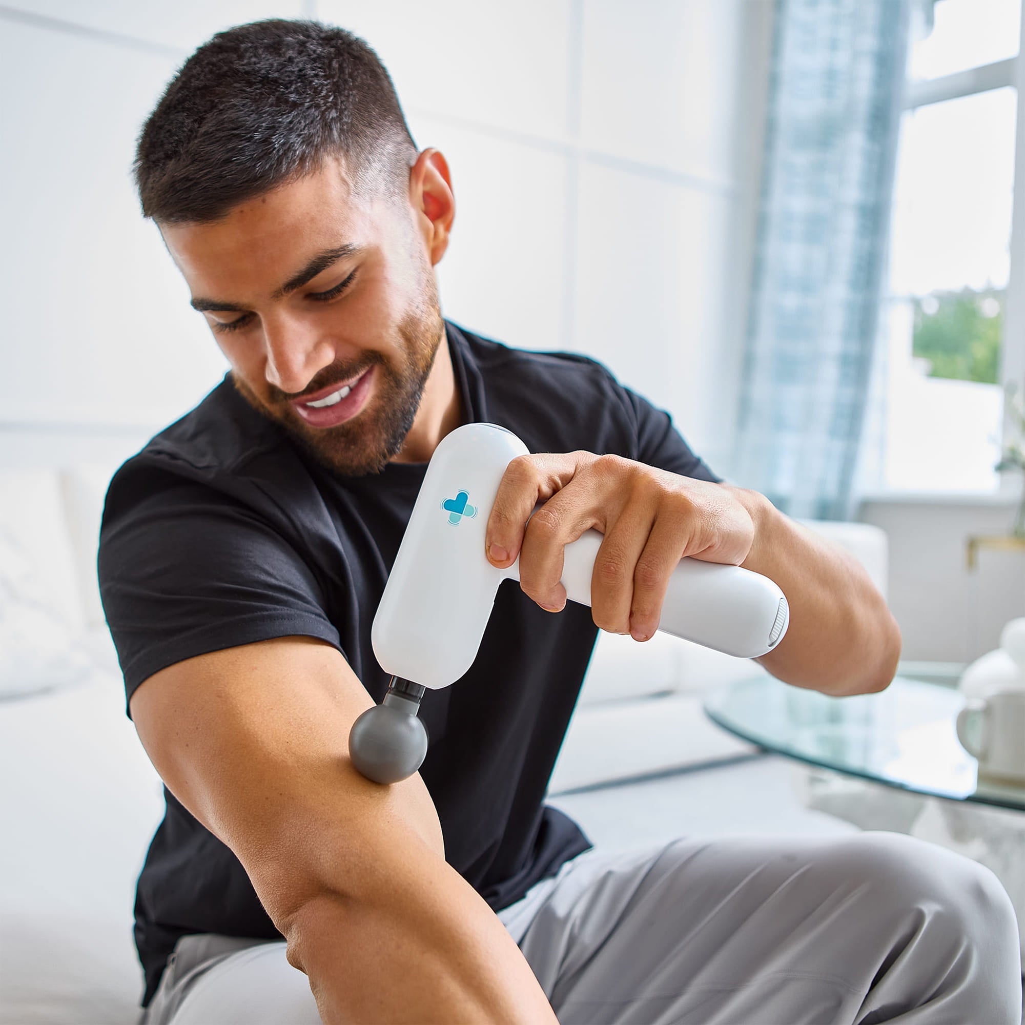 Man using Accuvibe Mini massager on forearm indoors