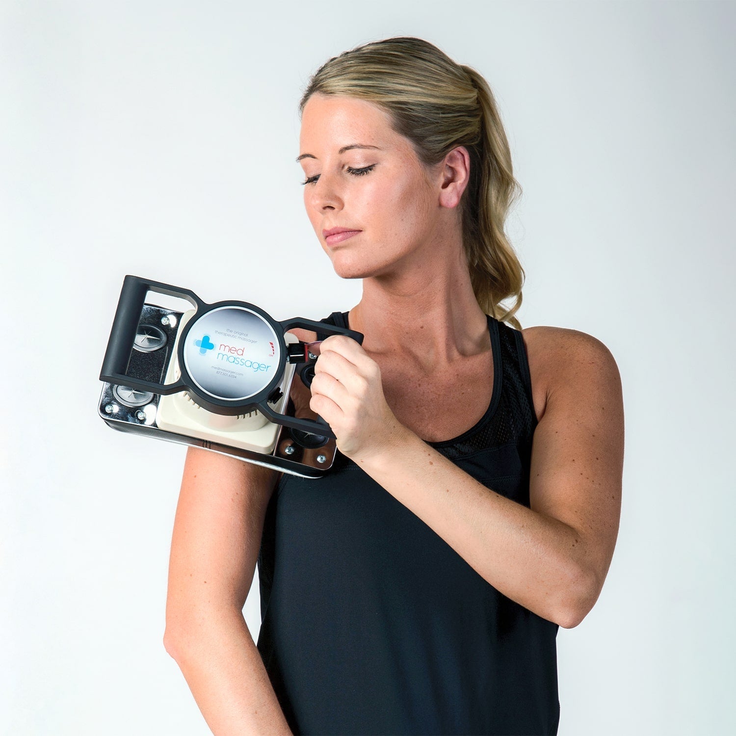 Woman using the MedMassager Body Massager Plus on her shoulder in front of a white background
