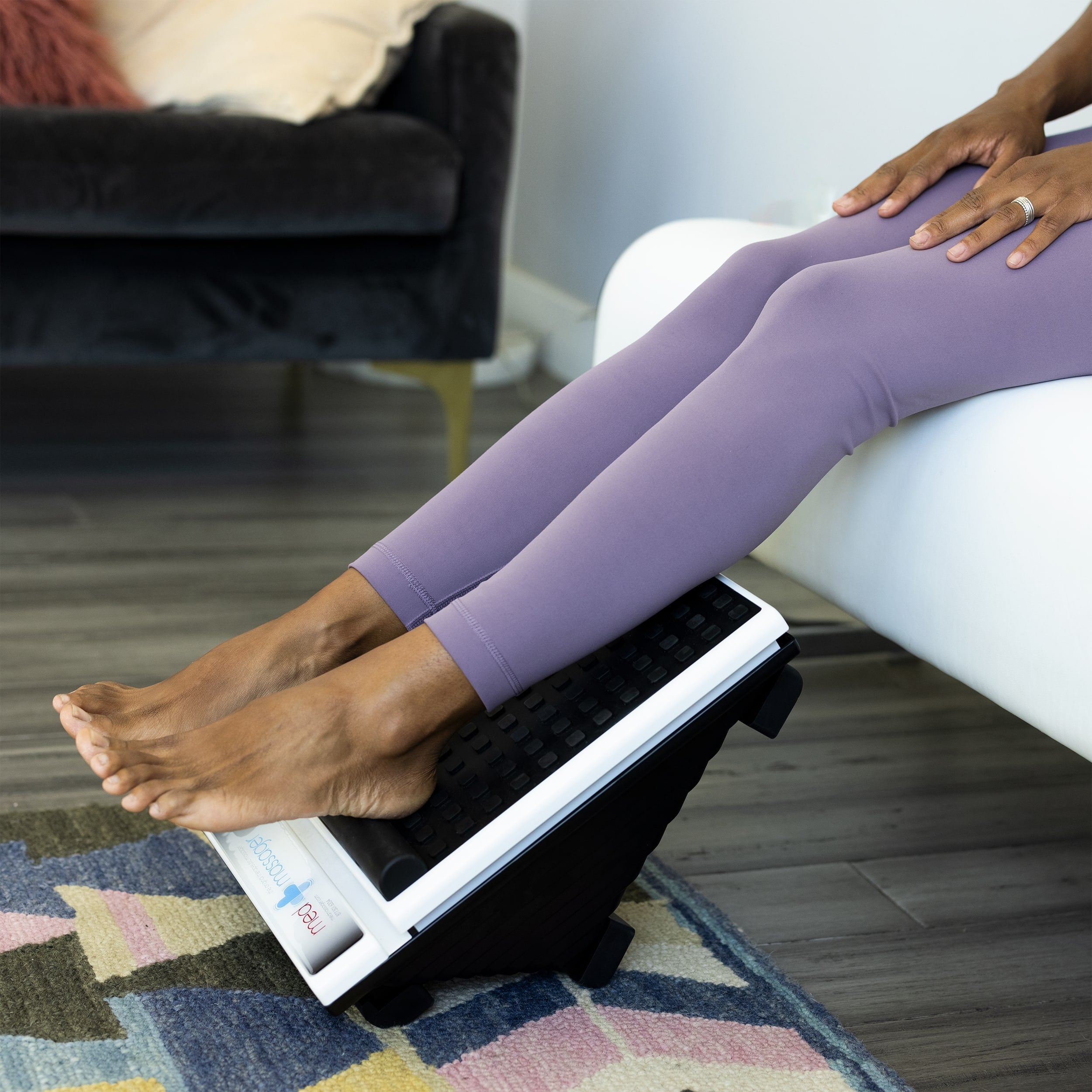 Close-up of feet using the Foot Massager Plus while seated on a white chair