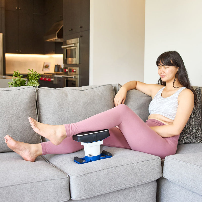 Woman relaxing on a couch using a MedMassager Body Massager on her back and thigh.