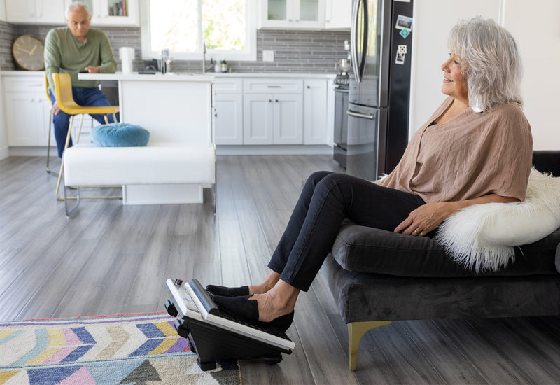 Woman relaxing on a sofa at home with her feet on a MedMassager Foot Massager Plus.