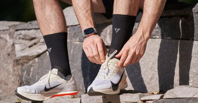 Close-up of a man tying his running shoes on stone steps, preparing for a run outdoors.