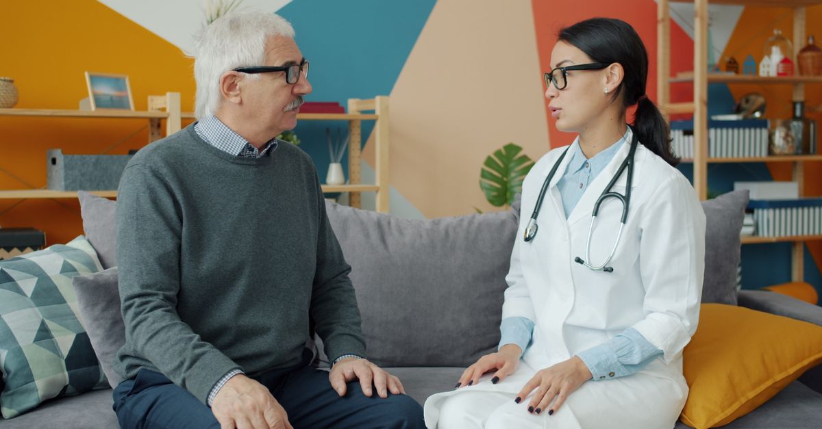 Older man talking with a doctor in a bright office.