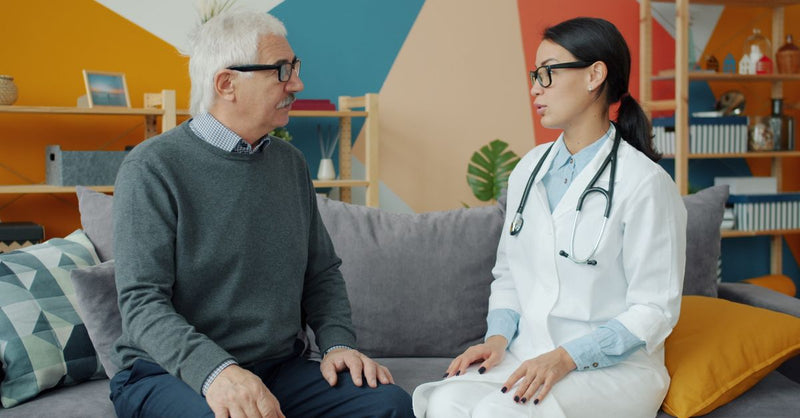 Older man talking with a doctor in a bright office.