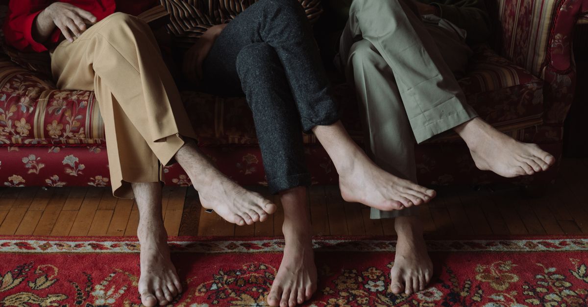 People sitting barefoot on a patterned sofa, showing comfort indoors.