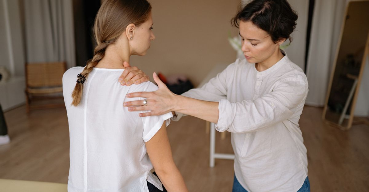 A therapist performing a shoulder massage on a woman to relieve physical tension.
