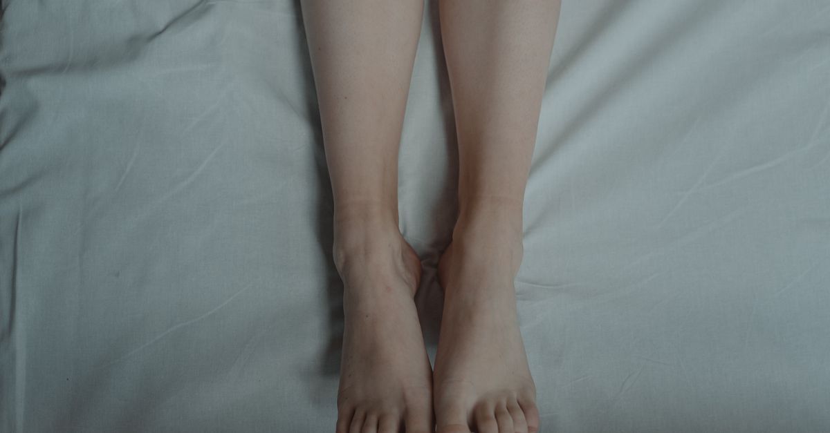 A pair of bare feet lying on a bed, capturing a serene and relaxed moment.