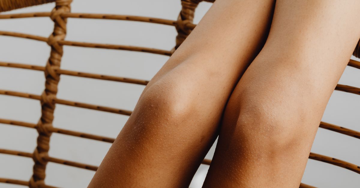 A close-up view of relaxed legs resting on a woven chair, highlighting smooth skin.