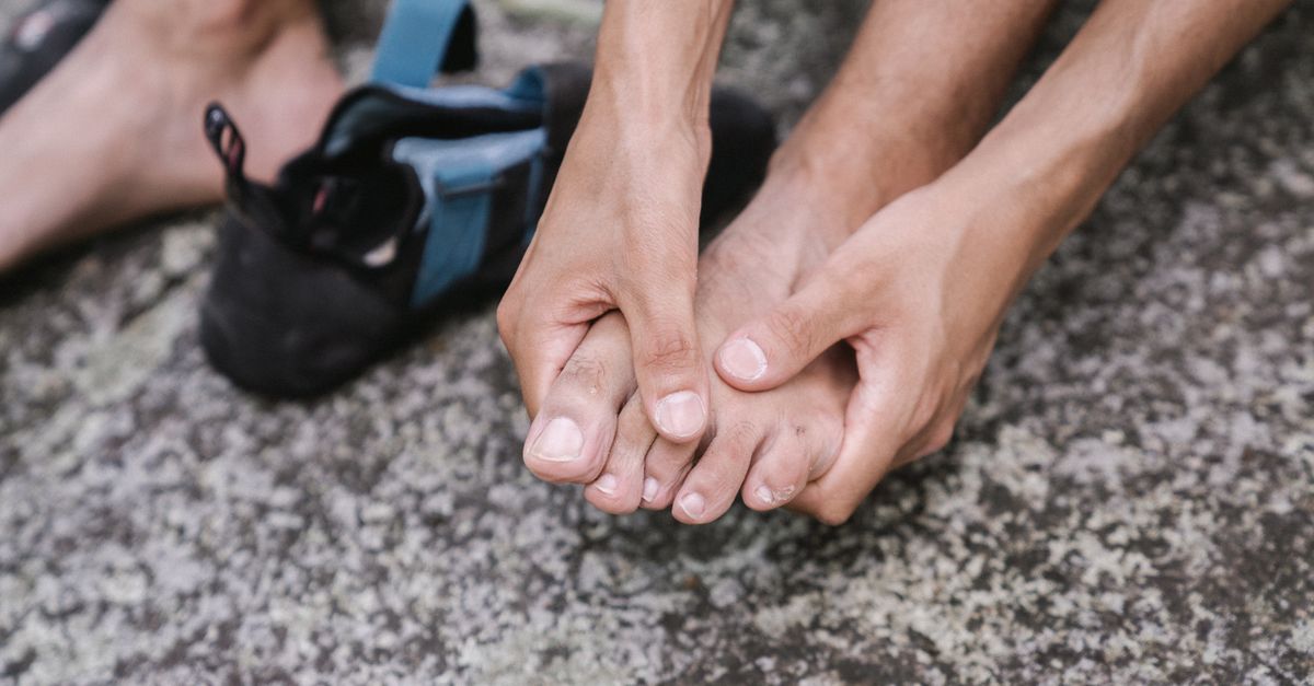 A person outdoors massaging their bare feet, conveying relaxation and care.