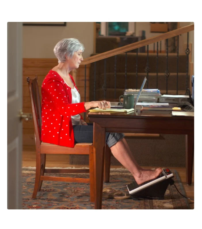 Woman sitting at a desk with bare feet on a MedMassager foot massager.